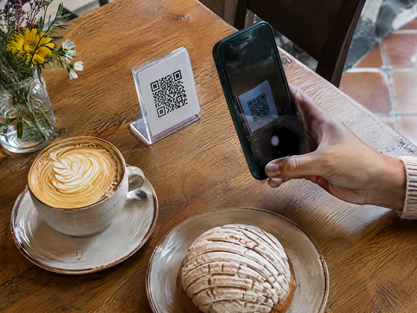Mesa de cafetería con un código QR, un café y un celular